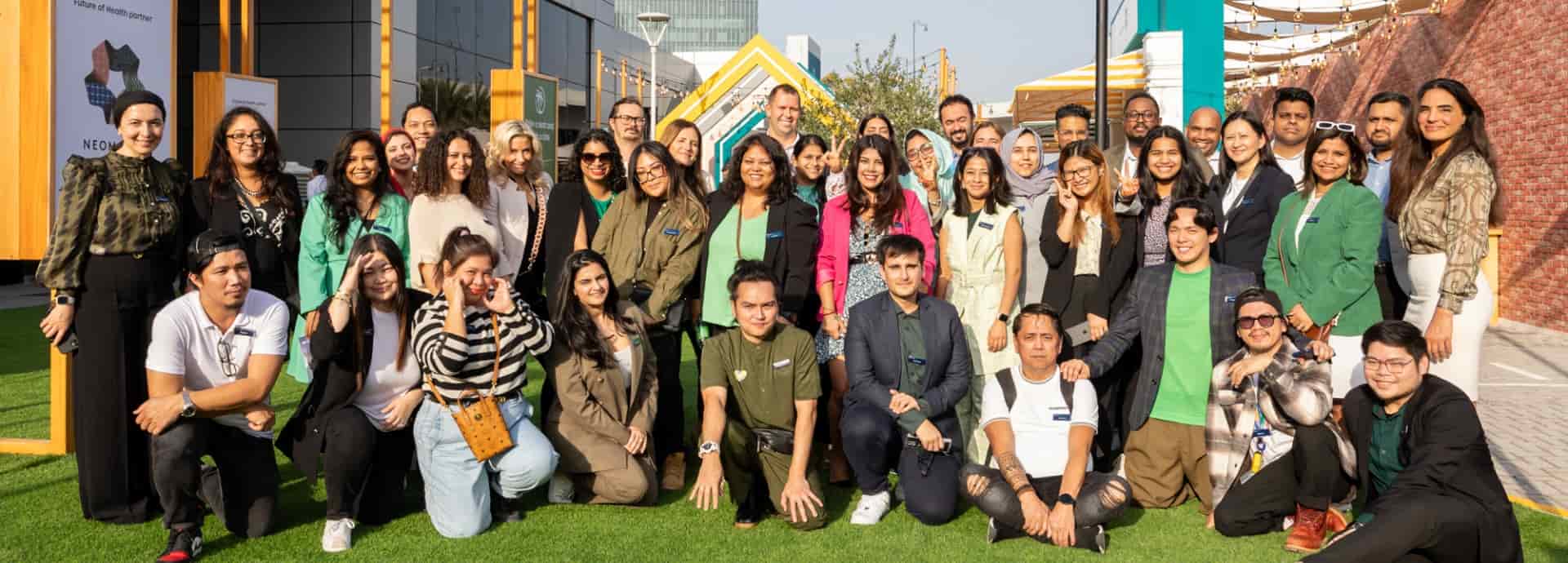 A group of people posing for a photo in front of World Health Expo Dubai