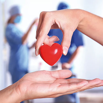 Image of hands holding a heart in a hospital setting