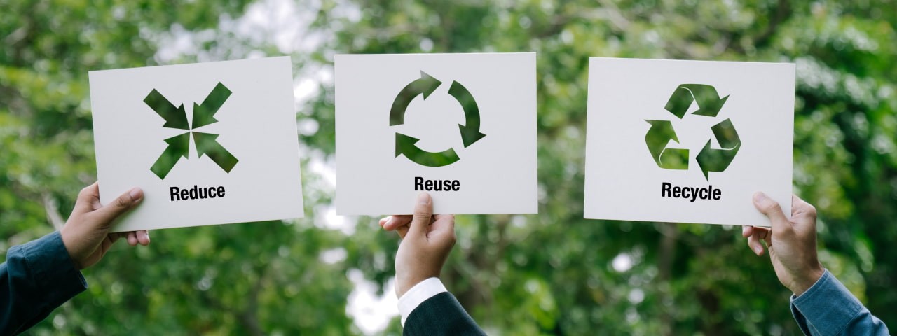 Signs being held up saying Reduce Reuse Recycle.